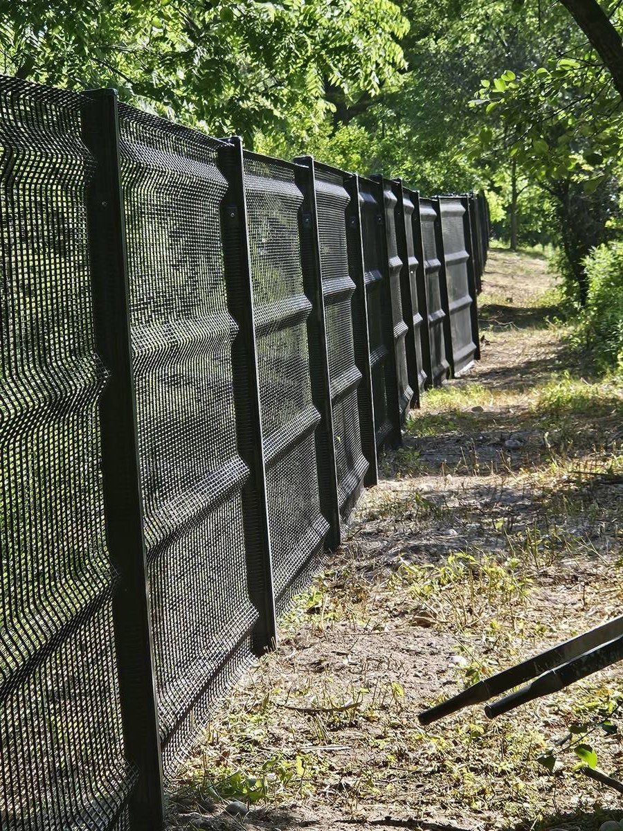 Black security mesh fence installed along a wooded property line