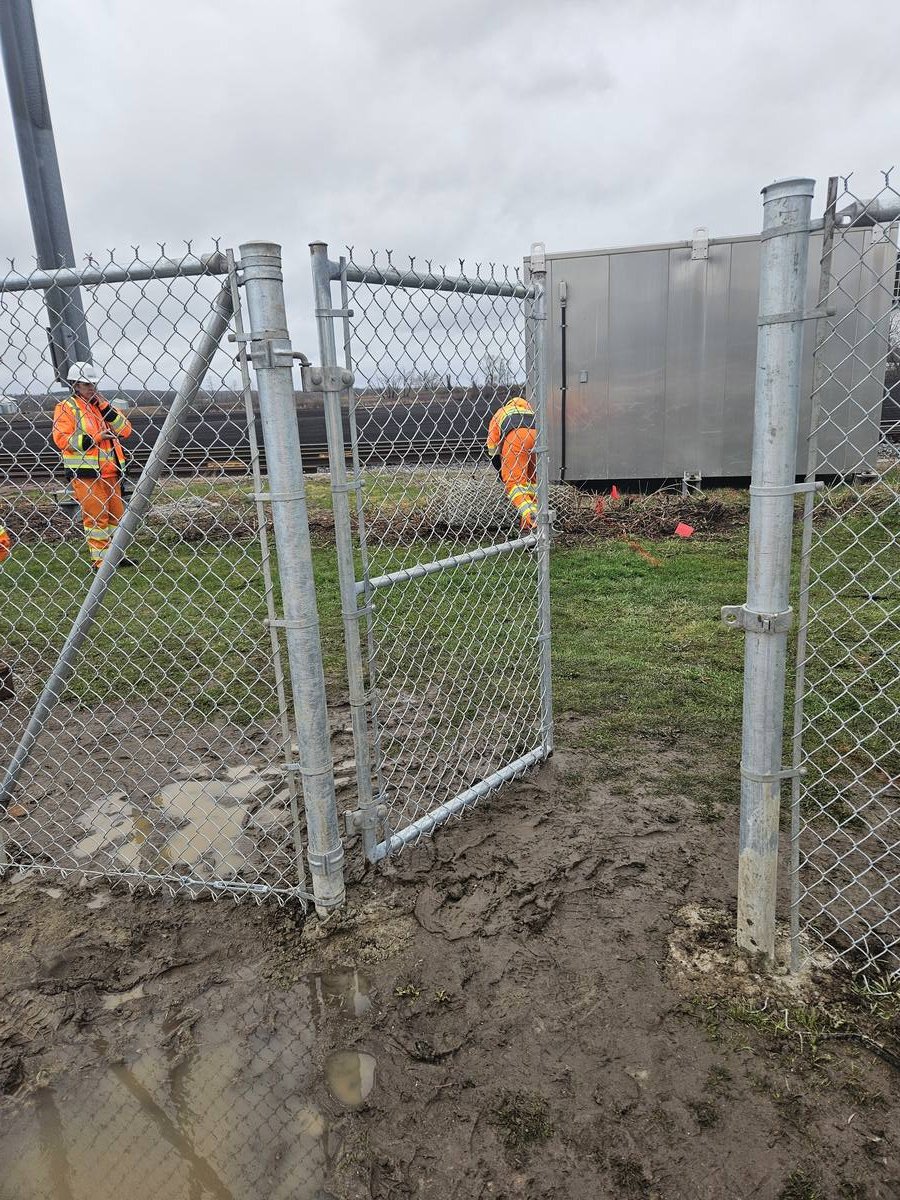 Crew installing a chain link access gate on site
